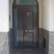 Puerta de entrada residencial con cerradura de seguridad y panel decorativo.